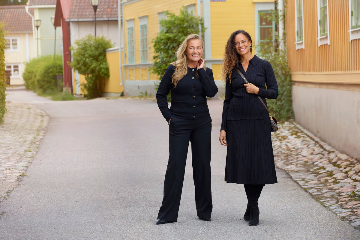 Festkläder för damer Yvonne Ryding med svarta kofta raka kostymbyxor och ett blått stickat sett med tröja och kjol