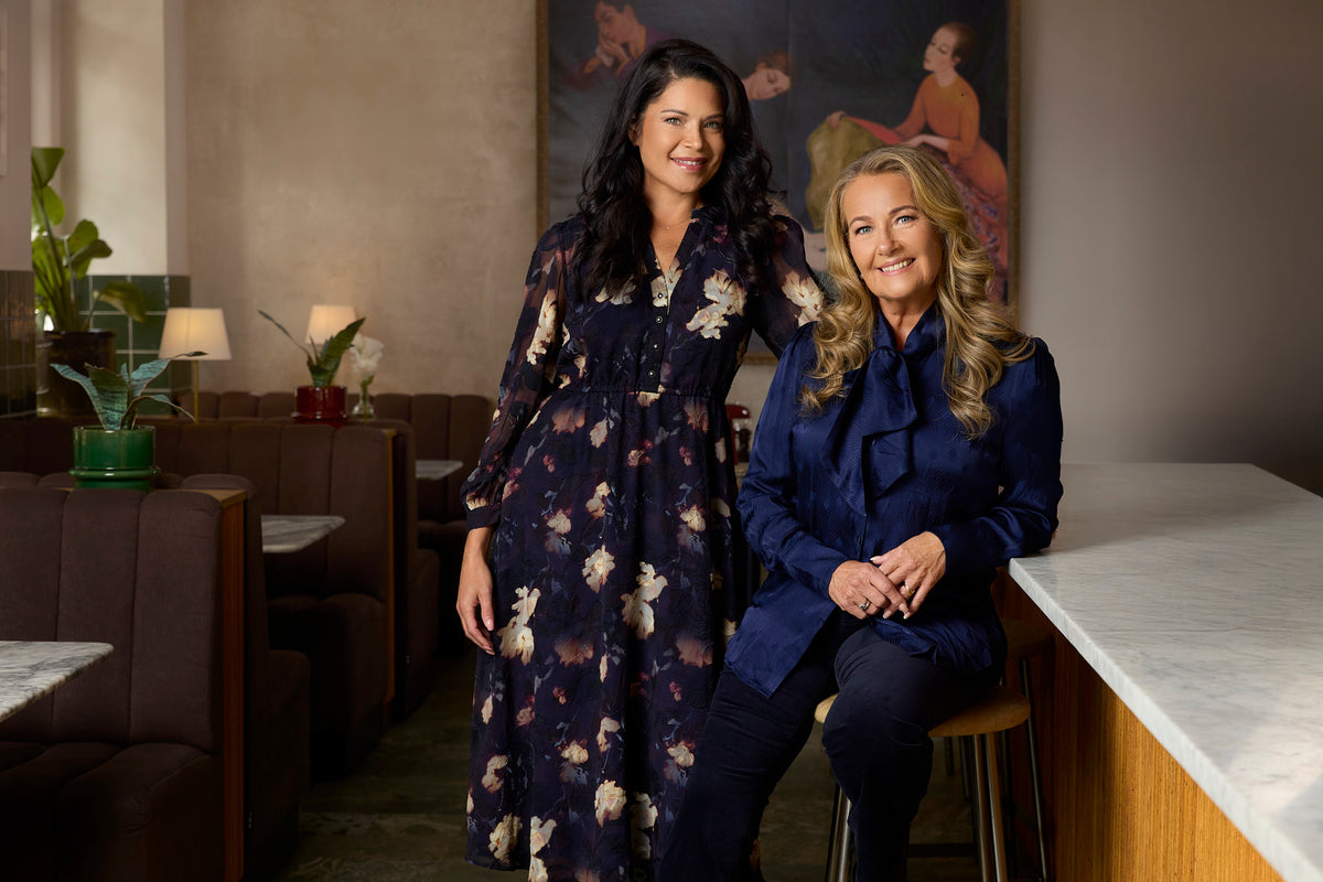 Jessica står i blommig klänning tillsammans med Yvonne Ryding som har en mörkblå knytblus med mörkblå sammetsbyxor